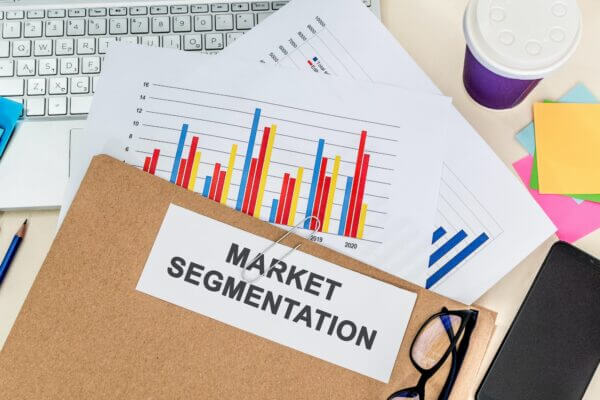 Top view of a folder labelled "MARKET SEGMENTATION" on a laptop with charts on it in the office